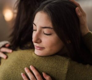 Young teenage girl hugging her mother at home.